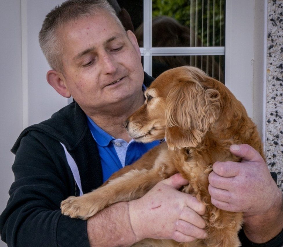 Steven Gallagher acariciando a su perro luego de recibir un trasplante de dos manos.